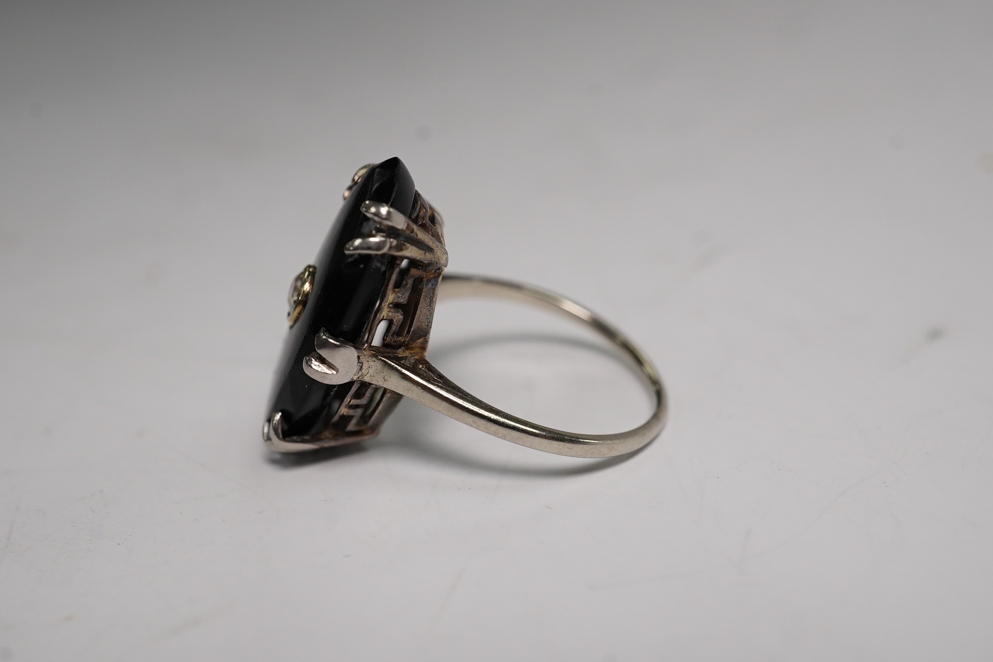 A white metal, black onyx and single stone diamond set oval ring, size M/N, gross weight 3.9 grams. Condition - poor to fair